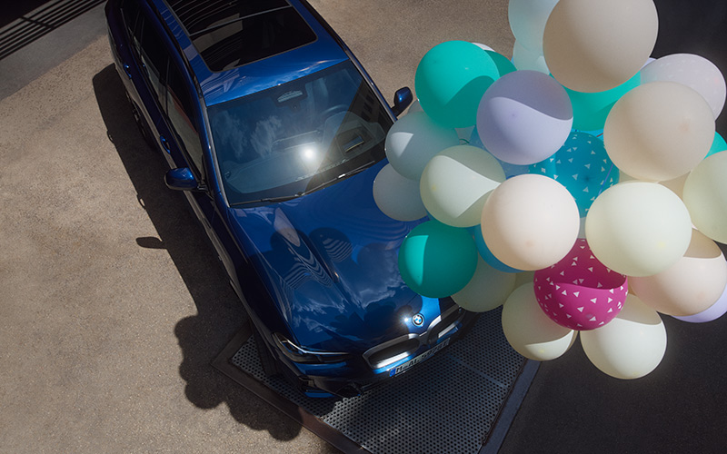 Blauer BMW SUV von oben mit Luftballons
