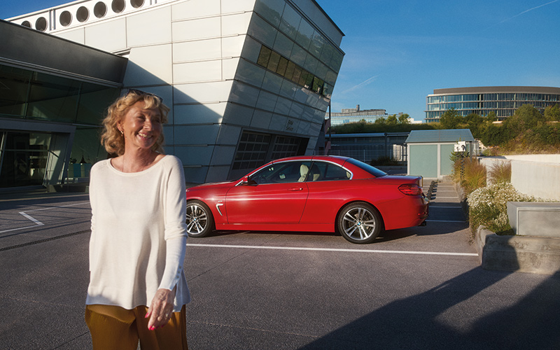 Rotes BMW Coupé auf Parkplatz mit Frau im Vordergrund