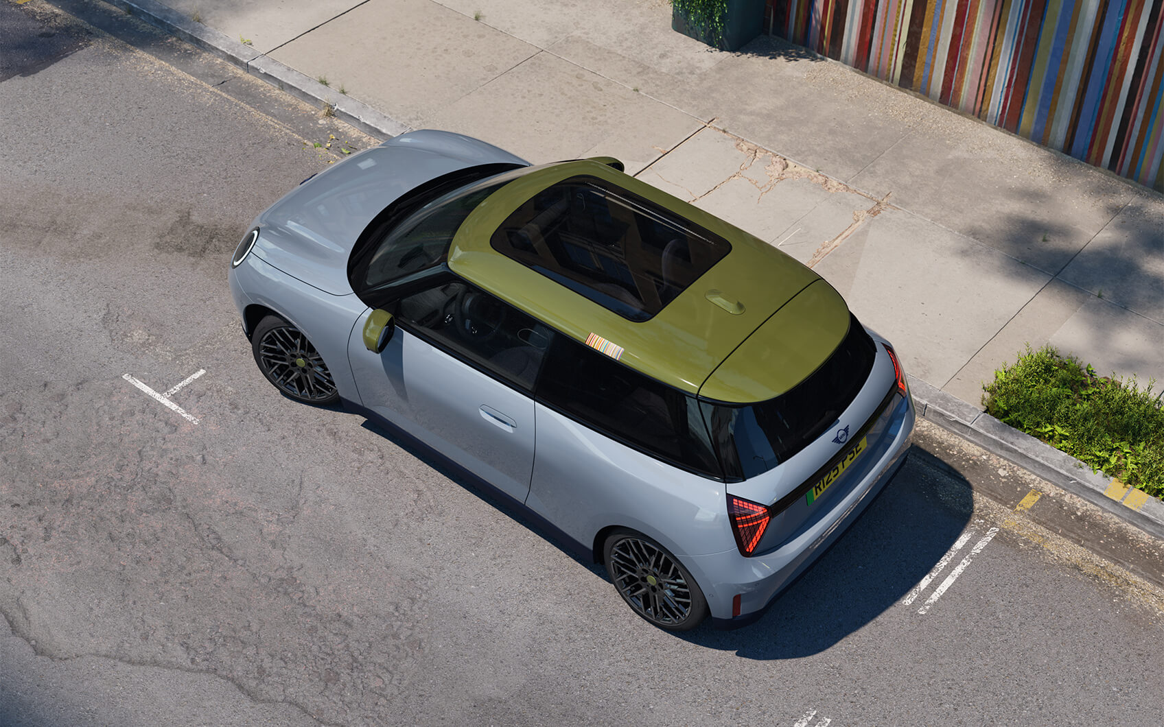 MINI Cooper Electric Paul Smith Edition mit hellem Exterieur, grünem Dach und Panoramadach aus der Vogelperspektive.