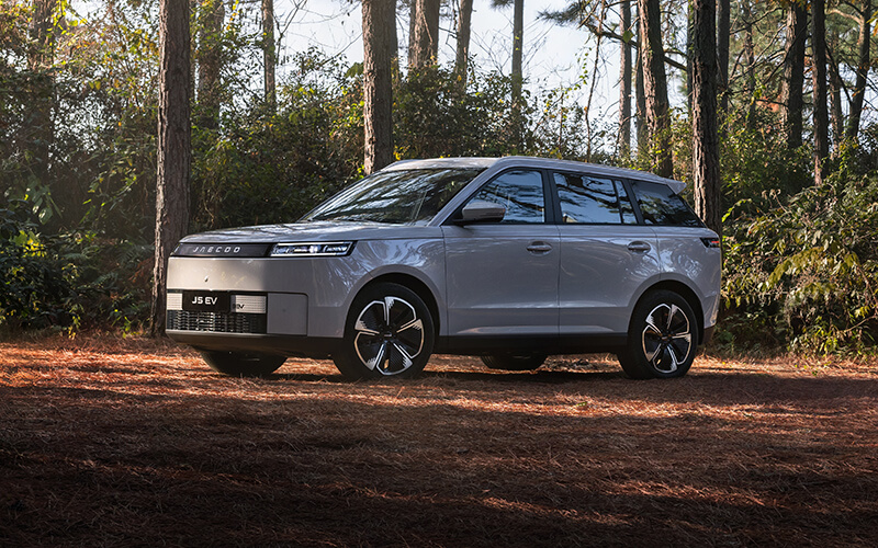 Grauer JAECOO J5 EV in einem Wald.